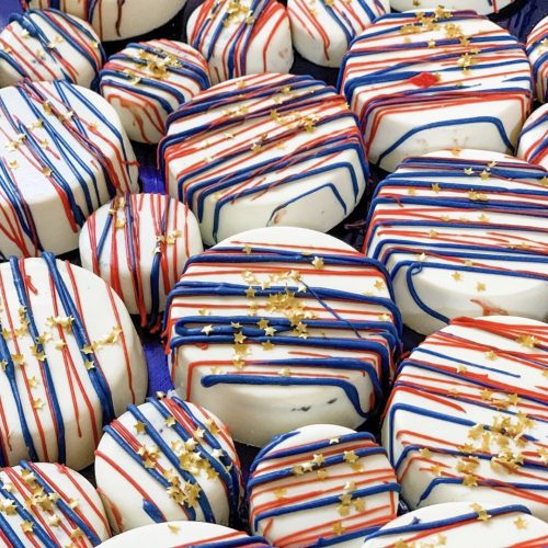 Oreo cookies covered in white chocolate with red and blue stripes and gold specks